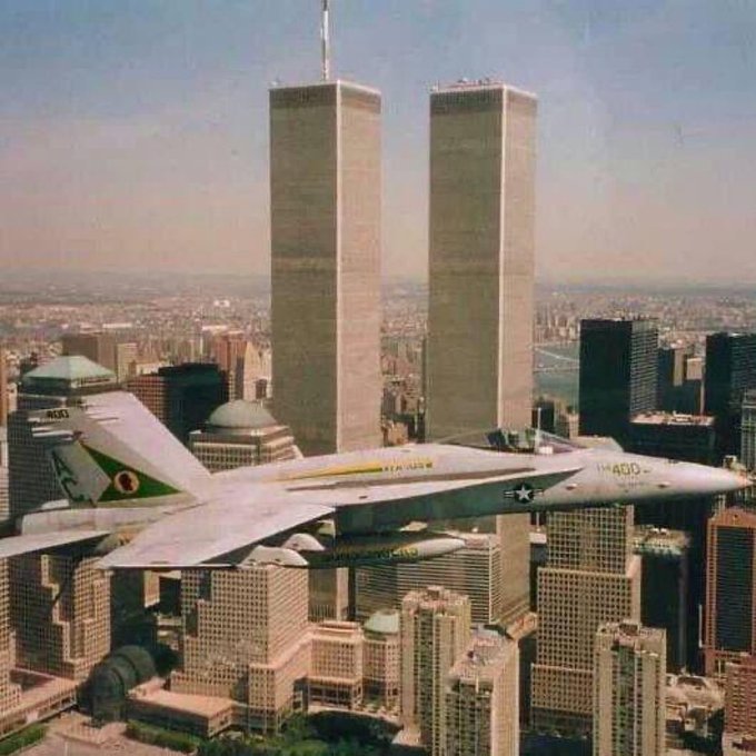 A photoshopped image showing a U.S. military F-14 Tomcat fighter jet (marked TF-106) flying in front of the Twin Towers in New York City.