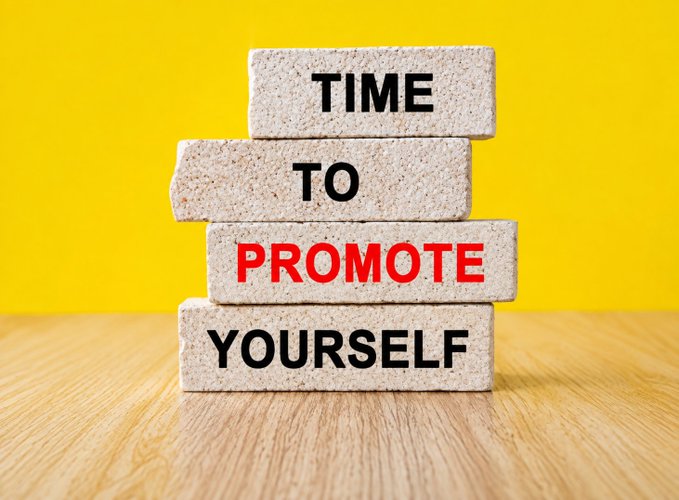 Four stacked stone blocks spell 'TIME TO PROMOTE YOURSELF' on a wooden surface against a yellow background.