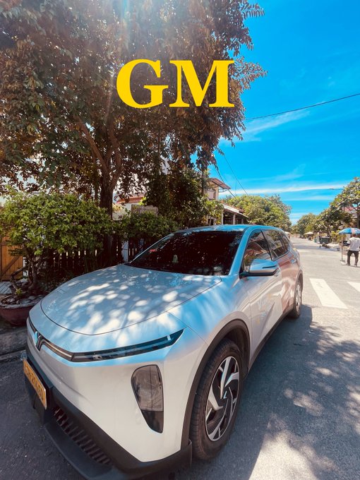 A silver NIO electric SUV parked on a sunny street with 'GM' written in large yellow letters.