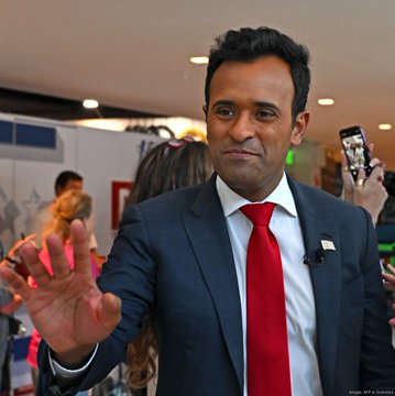 A man in a dark suit with a red tie waves while speaking, with a phone visible nearby.

The image appears to show Vivek Ramaswamy, the figure referenced in the post as backing Strive, the asset management firm that continues to accumulate Bitcoin, with the caption highlighting their recent purchase of 18 BTC worth $1.2 million.