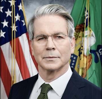 Official portrait of an older man with gray hair and glasses wearing a dark pinstripe suit and green tie, with the U.S. flag and a green state flag in the background.