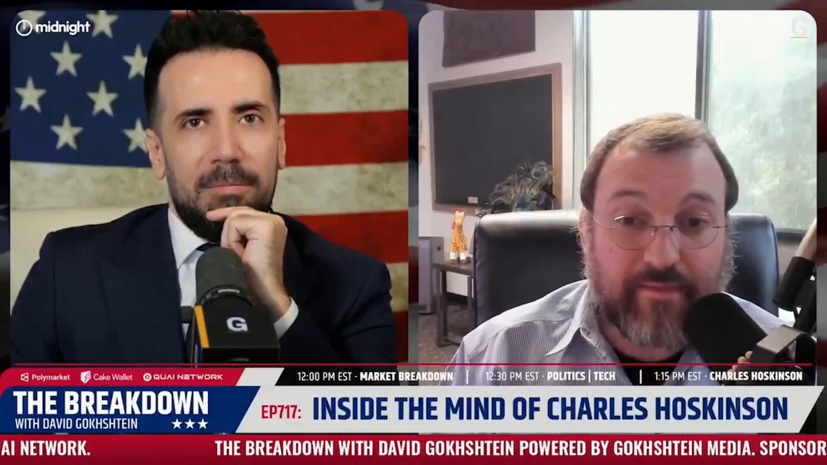 The image shows two men sitting behind microphones, with one man wearing a suit and tie and the other wearing glasses. They are both talking about blockchain technology, specifically the concept of "blockchain is dead." The first man is making a joke about the critics who fail to understand the true potential of this technology.