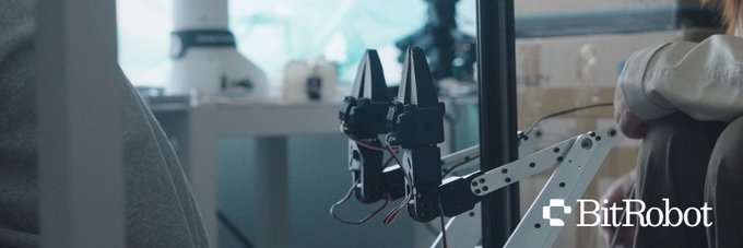 A promotional banner for BitRobot showing a mechanical robotic arm in what appears to be a workspace or cafe setting.