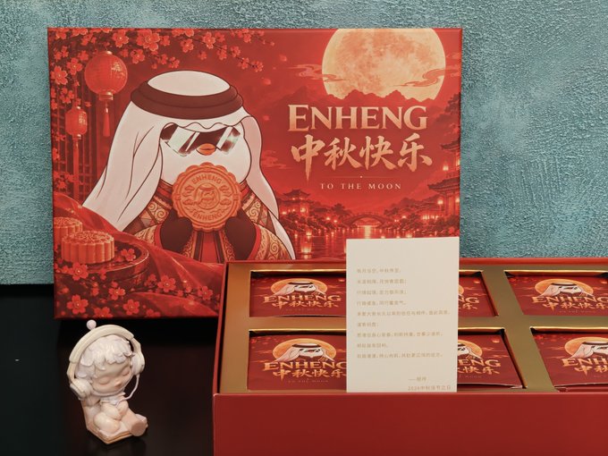 A Mid-Autumn Festival gift set from 'ENHENG' (恒辉) featuring red packaging with the phrase '中秋快乐 TO THE MOON', including a cute mascot figurine wearing sunglasses and a headscarf.