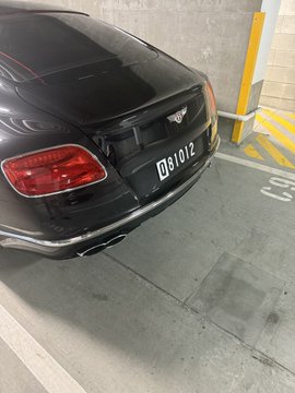The image shows a black Bentley Bentayga parked inside an underground parking garage, with its rear end facing towards the camera. The license plate of the car reads "081". Below this, there's some text that says "My man @eggybug42069 is building @NameWhisper_AI follow if you're into ID!".