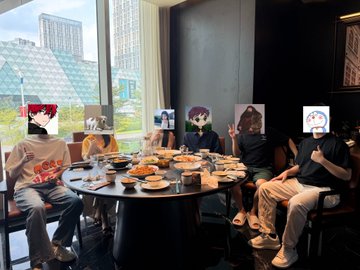 A group of people are seated around a circular dining table in a restaurant, with their faces obscured by anime-style character stickers and a 'Louis Vuitton' logo visible on one person's white t-shirt.