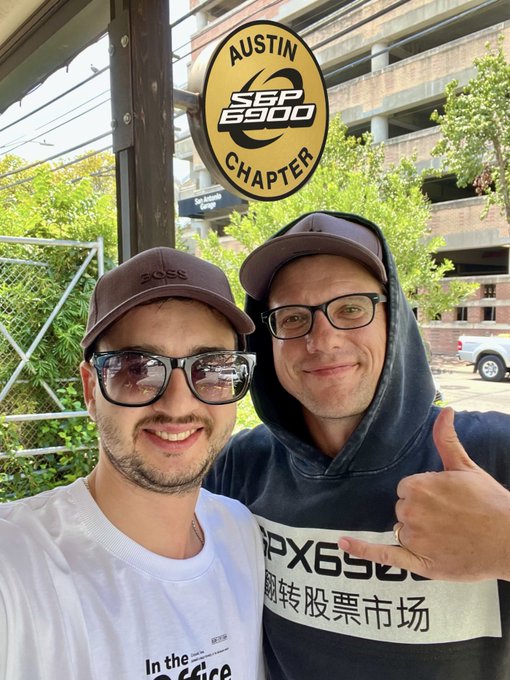 Two smiling men pose for a selfie under the "AUSTIN SPX 6900 CHAPTER" banner, with one wearing an "SPX6900" shirt featuring Chinese characters, visually reinforcing the post's message of consistency and persistence with the $SPX ticker and #SPX6900 / #SPXAustinChapter tags.