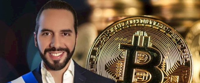 A smiling man wearing a suit with a blue sash (resembling a president) stands next to a large physical Bitcoin coin against a golden background.