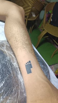 A man's hairy leg displays a small temporary tattoo of a foot with a barcode pattern on its sole, poking fun at the "BITFOOTS" misspelling of "bitcoin" to suggest lifelong holders have worn in the soles of their feet from walking a long road.