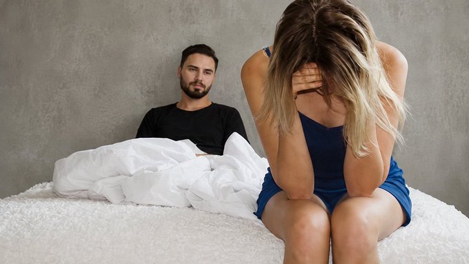 A woman sits on the edge of a bed, face buried in her hands in apparent distress, while a man sits propped against the wall behind her, watching silently amid rumpled white sheets. The post's reference to his "first tx" (likely meaning transaction or experience) on the Monad blockchain contrasts sharply with the intimate interpersonal drama depicted, suggesting a crypto-related revelation may have caused the emotional rift.