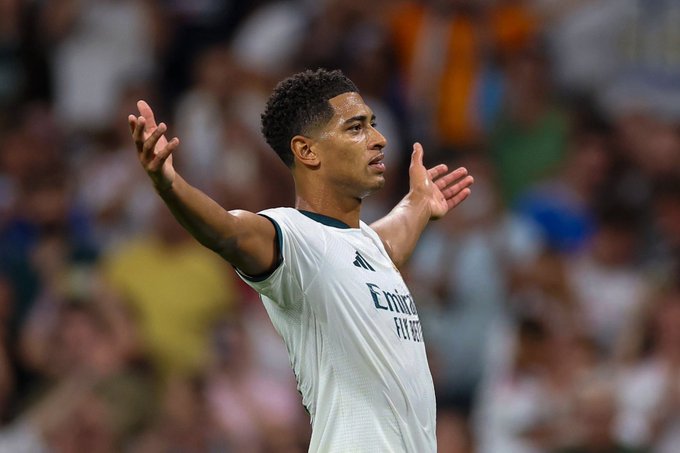 A soccer player in a white Real Madrid jersey with "Emirates FLY BETTER" sponsor text celebrates with outstretched arms, and the caption "مؤسس الـ AURA" ("The founder of AURA") suggests fans are praising him as the origin of the team's commanding presence or aura on the pitch.