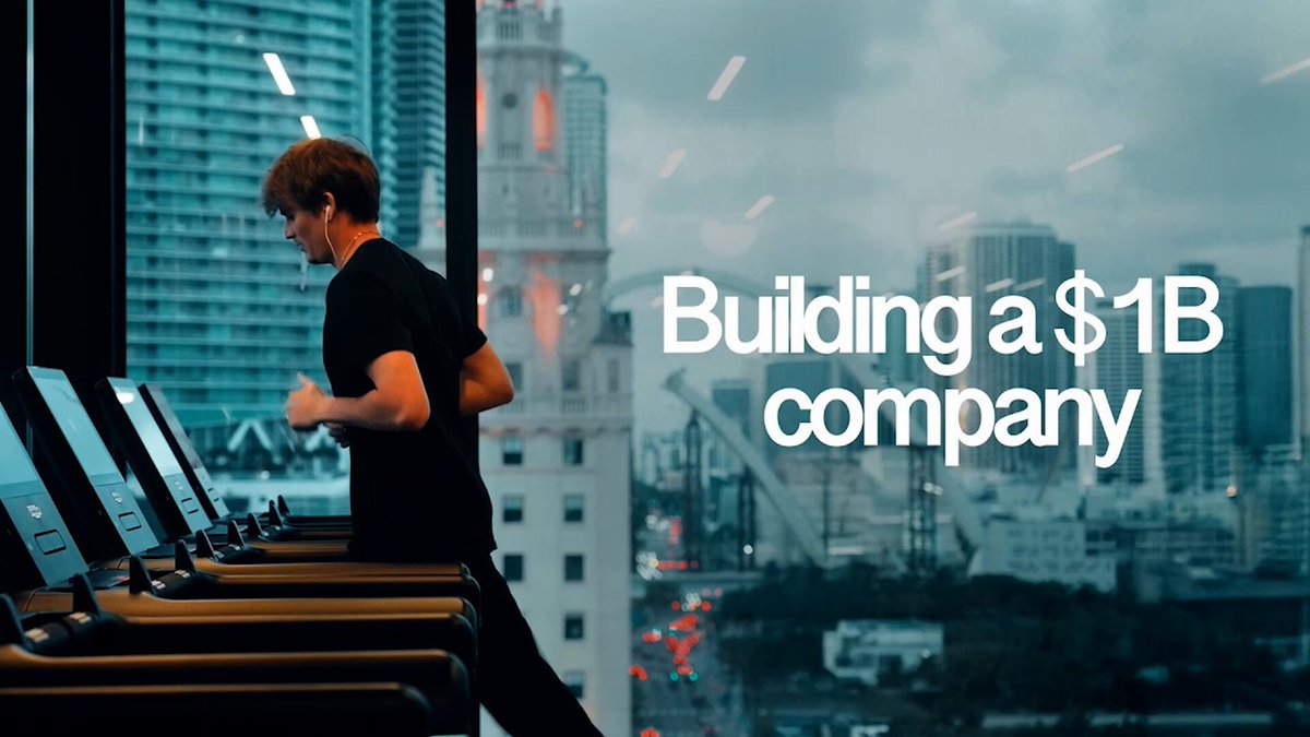 The image shows a man running on an exercise bike inside a gym, with a large window behind him that offers a view of a city skyline outside. The caption for the image reads "Building @SushiSwap | Episode 4".