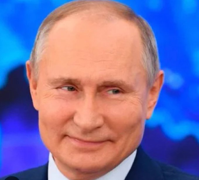 A close-up portrait of Russian President Vladimir Putin smiling slightly against a blurred blue background.