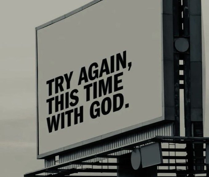 A billboard displays the text 'TRY AGAIN, THIS TIME WITH GOD.' in bold black letters on a white background.