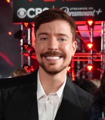 A man with a beard and mustache, appearing to be Jimmy Donaldson (known as MrBeast), smiles at the camera in front of a CBS and Paramount+ backdrop. The image accompanies a promotional post announcing MrBeast's $BEAST token listing on Binance, capitalizing on his recognizable face to lend credibility to the cryptocurrency presale.