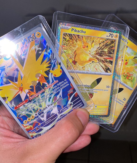 A hand holds three holographic Pokémon trading cards in protective sleeves, prominently featuring a French-language card 'Battements Pulsants' (Zapdos, 120 HP) and 'Pikachu' (70 HP) with rainbow foil effects.