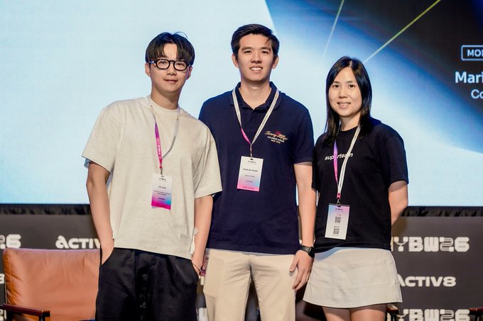 Three people wearing lanyards posing for a photo at an event, standing in front of a backdrop with 'ACTIV8' branding.