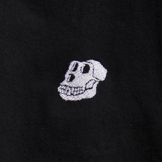 A close-up of a black fabric garment featuring a small white embroidered patch of a cartoonish skull.