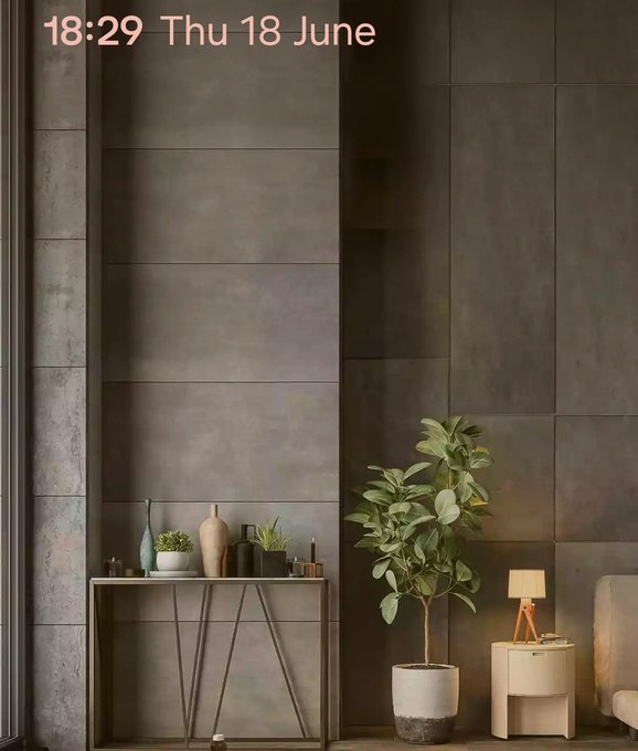 The image shows a living room with a gray wall, featuring two potted plants placed next to each other. The first plant is located near the left side of the frame, while the second one is situated more towards the right side. There are also several vases and bottles scattered around the room, adding to its aesthetic appeal. A table can be seen in the center of the image, with a lamp on it providing additional lighting. The overall atmosphere appears to be calm and inviting, making for an ideal space to relax or unwind after a long day.