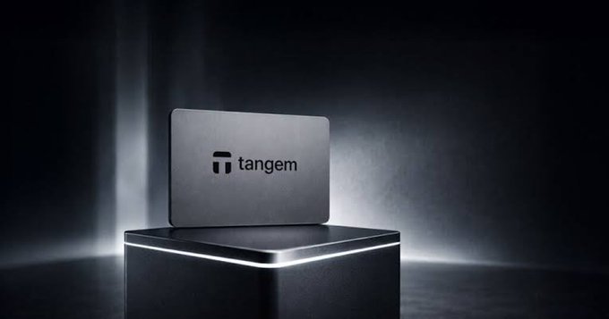 A sleek black Tangem wallet is prominently displayed on an illuminated pedestal, with the brand name "tangem" visible on its surface. The dramatic, minimalist presentation emphasizes the wallet's premium, secure design—reinforcing the post's message of self-custody and taking full control of your digital assets.