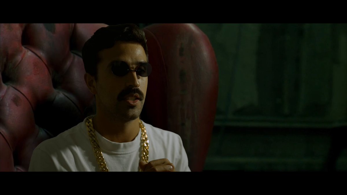 The image features a man wearing sunglasses, sitting in an armchair with his hand on his chin. He has a gold chain around his neck. In the background, there are two chairs - one red and one black. The text "$XRP is the exit...", which translates to "XRP is the exit...", is visible in the image as well.