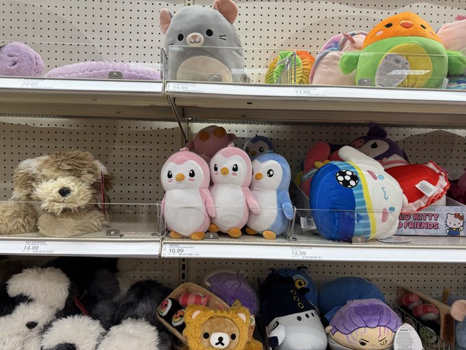 A store display featuring shelves of Squishmallows plush toys, including penguins, bears, and Hello Kitty & Friends characters, priced at $14.00, $10.99, and $12.99.