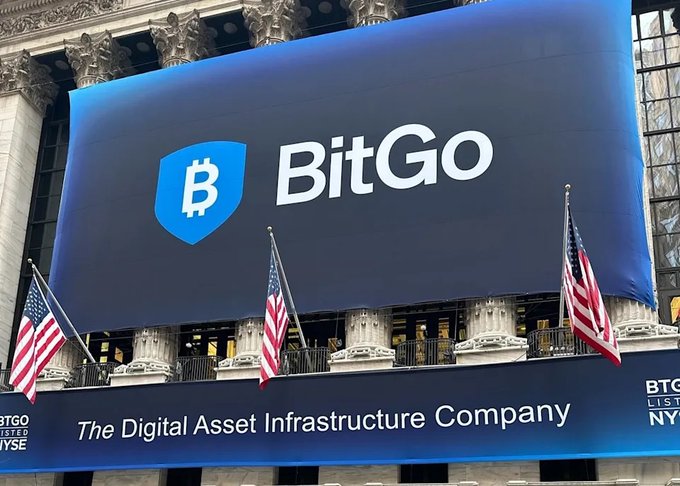 A large blue banner outside the New York Stock Exchange displays "BitGo - The Digital Asset Infrastructure Company" alongside American flags, promoting the company's listing on the NYSE in connection with its new quantum computing risk protection solution for institutional Bitcoin wallets.