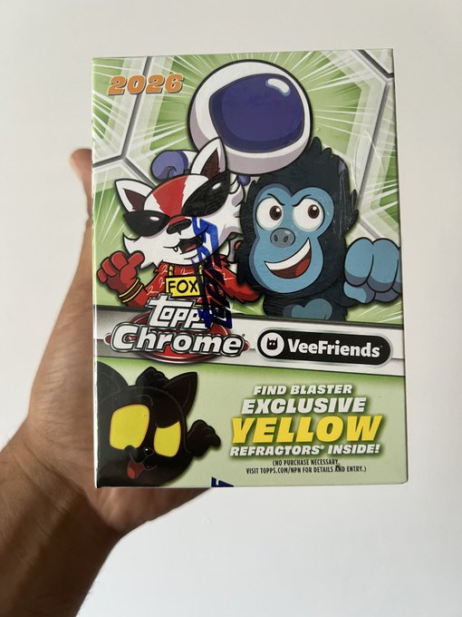 A hand holding a sealed 2026 Topps Chrome VeeFriends trading card box, advertised with 'Find Blaster Exclusive Yellow Refractors Inside'.