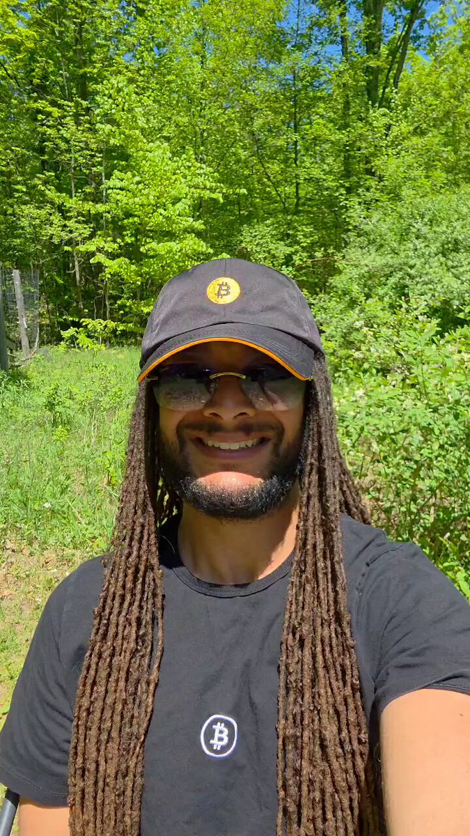 The image features a man with dreadlocks wearing a black shirt, standing outdoors in front of trees. He has long hair and is smiling for the camera. The caption reads "I'M STOKED to announce that I will be the new Social Media News Reporter @_btcinc". This suggests that the man might have an interest in social media or news reporting, possibly related to Bitcoin or other topics of interest.