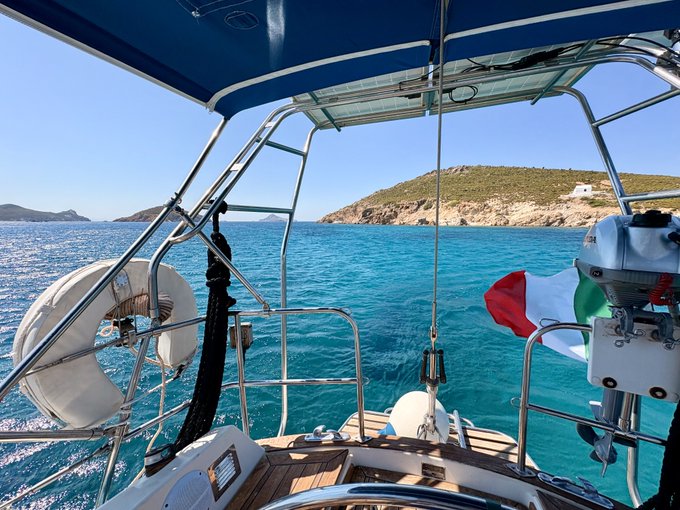 A view from the stern of a boat cruising through turquoise waters toward a rocky coastline, with an Italian flag fluttering in the breeze—capturing the perfect Sunday escape on the Mediterranean. "Good Sunday Friends!"