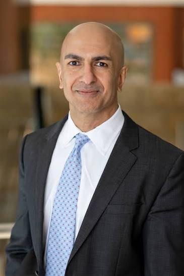 A professional headshot of a man wearing a dark suit, white shirt, and light blue patterned tie, smiling at the camera. The image corresponds to Neel Kashkari, the Minneapolis Federal Reserve President referenced in the caption discussing his concerns about persistent inflation despite recent cooler-than-expected price data.