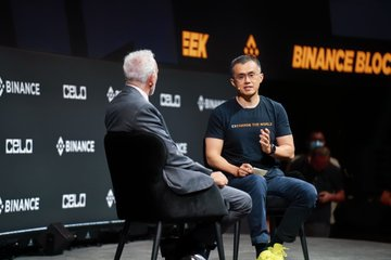 Two men sit on stage in conversation at a "Binance Block" event, with one wearing a "Binance" branded shirt and the other in a gray blazer, against a backdrop displaying "CB.EDU" and "BINANCE" logos. The image appears unrelated to the accompanying post, which discusses the 2014 Mentougou incident and a hypothetical gain of $6.4 million from 100 BTC.