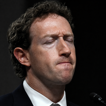 A man in a suit sits at a microphone with his eyes closed and a tight-lipped expression, appearing visibly troubled. The image likely illustrates the reaction of a corporate executive—possibly Meta's Mark Zuckerberg—to news that Bitcoin has overtaken Meta's market capitalization, surpassing it to become the 13th-largest global asset.