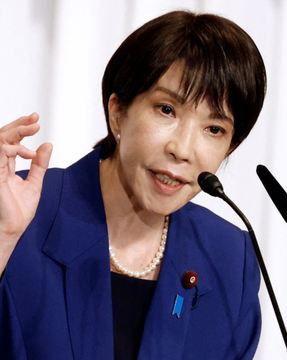 The image shows a woman in a blue suit and pearl necklace speaking at a podium, likely indicating a formal announcement or presentation related to the "Carry Trade" which is mentioned in the accompanying post and hashtag #RCT.