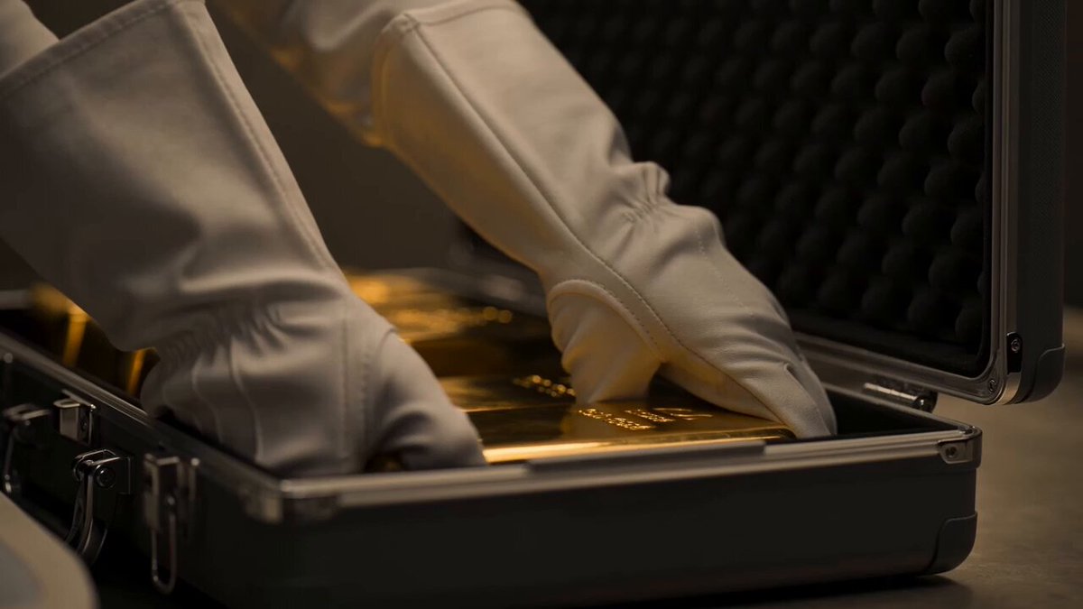 The image shows a pair of white gloves with gold trim, suggesting that they are made from real gold or have some sort of gold-like material. The gloves appear to be inside an open briefcase, which could potentially contain valuable items such as gold bars or coins. The gold content in the briefcase is highlighted by the text "Gold has carried value across generations. But physical gold still comes with friction: Weight Divisibility Movement In a digital world, it doesn't have to be this way. XAU₮ makes it easier to access gold in a modern financial system." This implies that the gloves and briefcase are related to the concept of gold divisibility or weight division movement, which is an important aspect of understanding how gold works as a currency or investment.