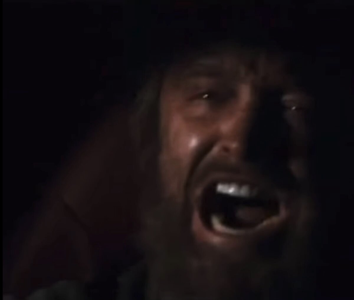 The image features a man with a long beard standing next to a couch. He appears to be shouting or yelling, possibly reacting to something that has occurred. The surrounding area seems dark, with shades of black dominating most of the scene. A car can also be seen in the background, further emphasizing the dark setting. In the corner of the image, there is an overlay that reads "That one bro who bought $BTC at 
$109k, $SOL at 
$295 and $ETH at $410", indicating a possible connection between the man's actions and a specific event or exchange involving cryptocurrency.