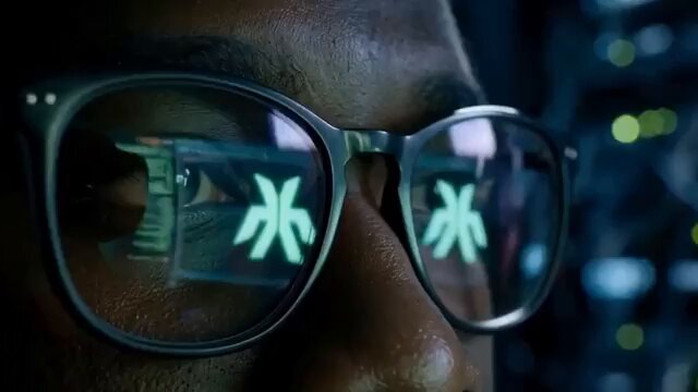 The image shows a close-up of a person's face wearing glasses with neon green letters, which are likely computer-generated or generated by a machine learning model. The glasses have a futuristic appearance that suggests they might be used for gaming or other interactive activities. The background is dark and blurred, drawing attention to the glasses and their unique design.