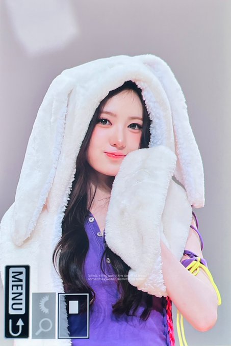 A young woman wearing a white fuzzy bunny-ear hood over a purple top, smiling at the camera in what appears to be a game menu screen.