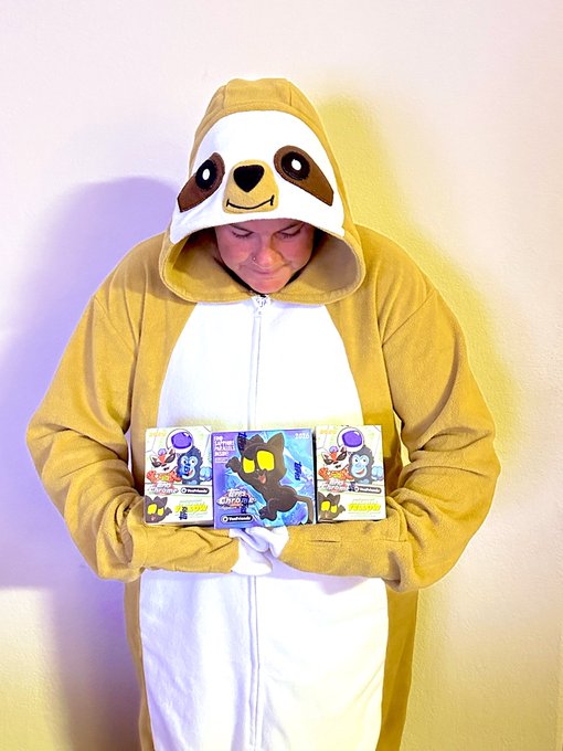 A person wearing a brown and white sloth onesie holds three Tokidoki Cactus Jack figures and boxes in front of them.
