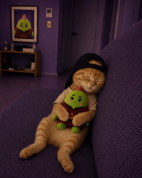 An orange tabby cat wearing a backwards black cap sleeps peacefully on a purple couch while hugging a small green plush toy, with a matching painting on the purple wall behind.
