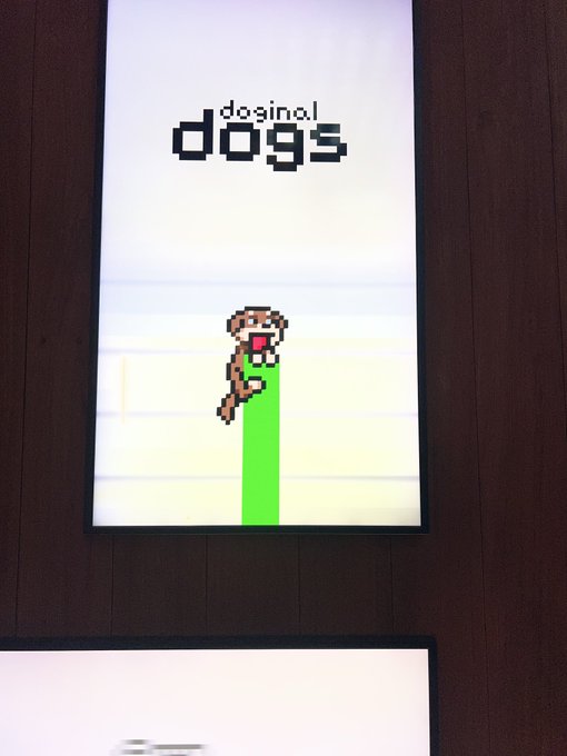 A digital display screen mounted on a dark wooden wall shows pixel art of a dog climbing a green vine under the text 'doginal dogs'.