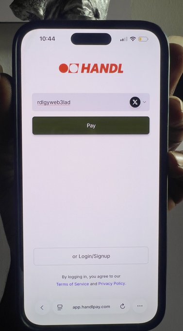 A phone displaying the HANDL payment app login screen at app.handlpay.com with a Pay button.