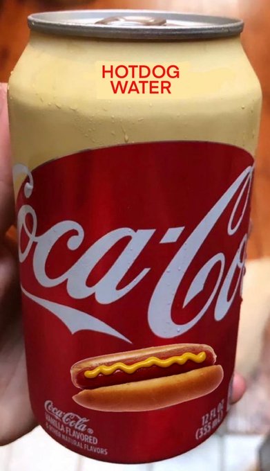 A hand holds a modified Coca-Cola can with the words "HOTDOG WATER" printed on the top, and the classic logo and image replaced with a picture of a hot dog in a bun.