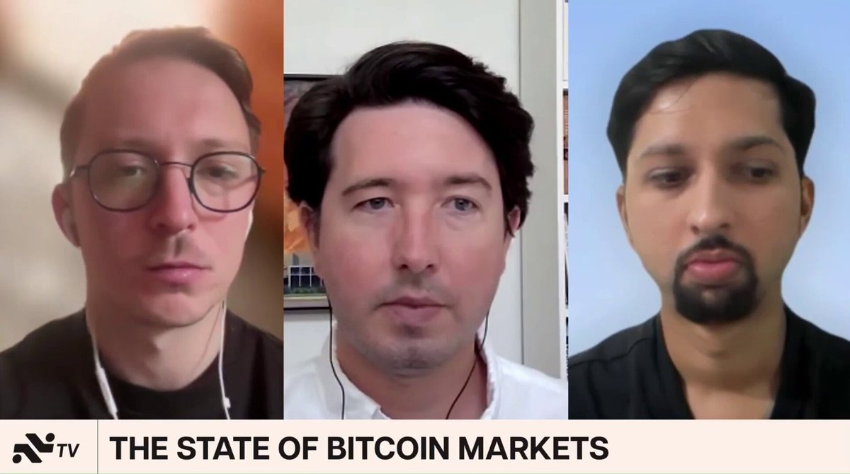 The image features three men with different hairstyles, all wearing glasses, sitting next to each other. They appear to be participating in a video call or panel discussion about Bitcoin markets. The background shows a gray wall, which serves as a neutral backdrop for the group of people and their conversation.
