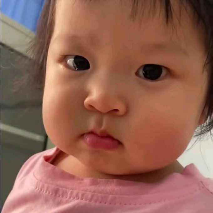 A close-up selfie of a young child with dark hair wearing a pink shirt.