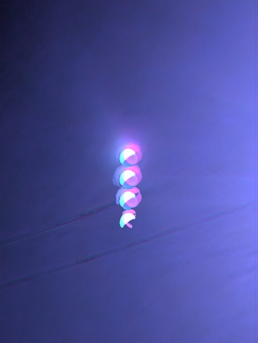 An abstract image of glowing blue and pink overlapping orbs stacked vertically against a deep blue background, resembling a stylized double-helix or light installation.