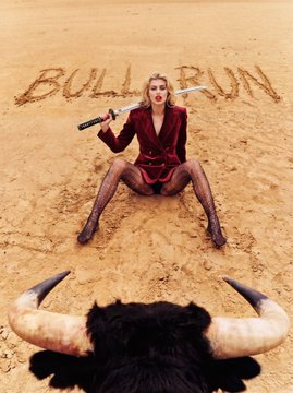 A woman in a red outfit sits poised in the desert holding a knife, facing an approaching bull whose horns are visible in the foreground, with "BULL RUN" written in the sand behind her—capturing the post's theme of boldly confronting the market rally.

Key text visible: "BULL RUN" (written in the sand).