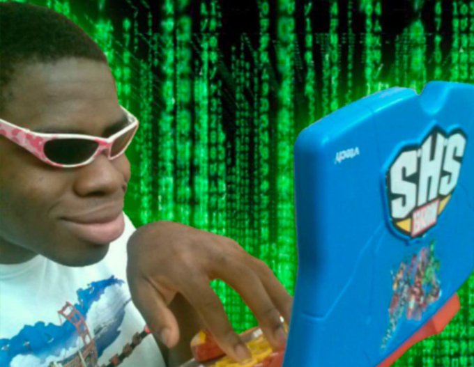 A man wearing pink flame-patterned sunglasses uses a blue Acclaim 'SKS' toy laptop against a green digital 'Matrix-style' cascading code background.
