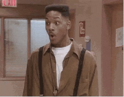 The image features an actor dressed in a brown shirt, with suspenders, standing in front of a window. He appears surprised or shocked by something happening outside. The background shows a hallway, which might be part of a building or room where the actor is located. There are also some words visible in the image that seem to be related to a post on social media, possibly discussing the actor's appearance and reaction.