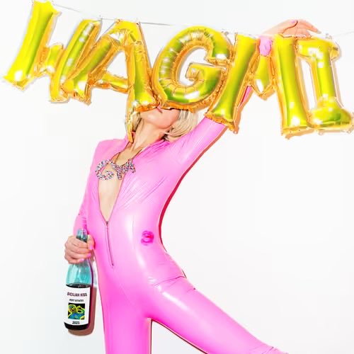 A person in a bright pink bodysuit posing while holding gold 'MAGIC' letter balloons and a bottle of sparkling beverage.
